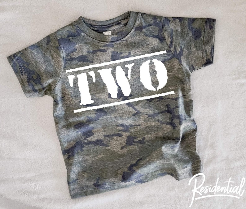May include: Camouflage green t-shirt with white text that says "TWO" in a bold, blocky font.