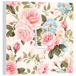 Puede incluir: Una tapa de interruptor de luz blanca con un patrón floral con rosas rosas y azules sobre un fondo crema.