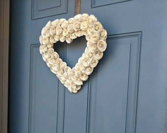 May include: A blue door with a white paper heart wreath hanging on it. The wreath is made of paper rosettes. The door has a gold door knocker and the words "hello..." written on it.