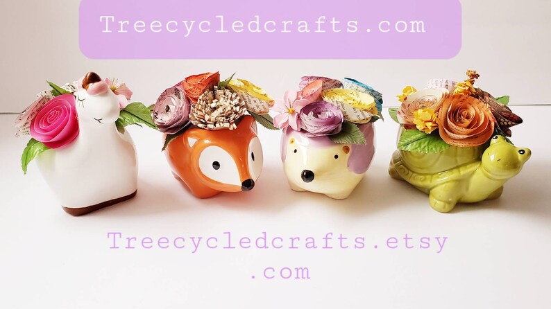 May include: Four small ceramic planters in the shapes of a unicorn, fox, hedgehog, and turtle, each with a colorful paper flower arrangement. The planters are arranged in a row on a white surface. The text "Treecycledcrafts.com" is visible at the top of the image, and the text "Treecycledcrafts.etsy.com" is visible at the bottom of the image.
