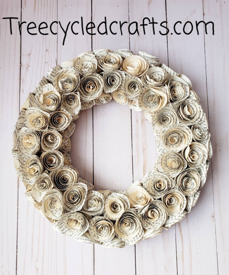 K&ouml;nnte beinhalten: Ein kreisf&ouml;rmiger Kranz aus gerollten Papierrosen, der verschiedene Creme- und Beiget&ouml;ne aufweist. Die Rosen bestehen aus Buchseiten und erzeugen eine einzigartige Textur. Der Text "treecycledcrafts.com" ist oben sichtbar.