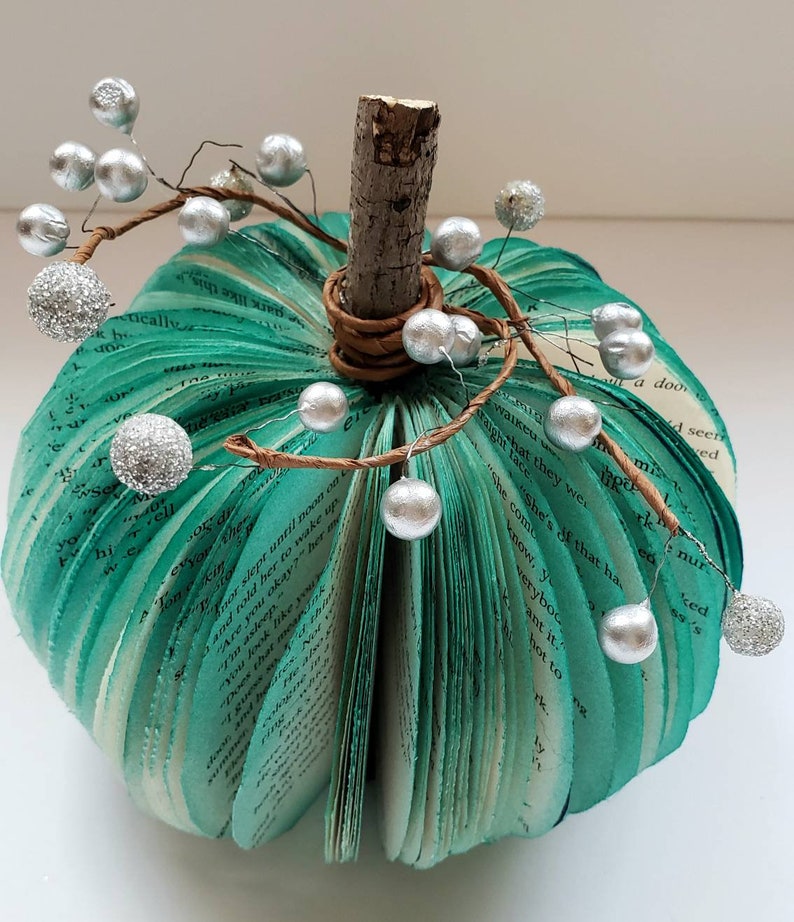 Teal book page pumpkin with silver berries as embellishments