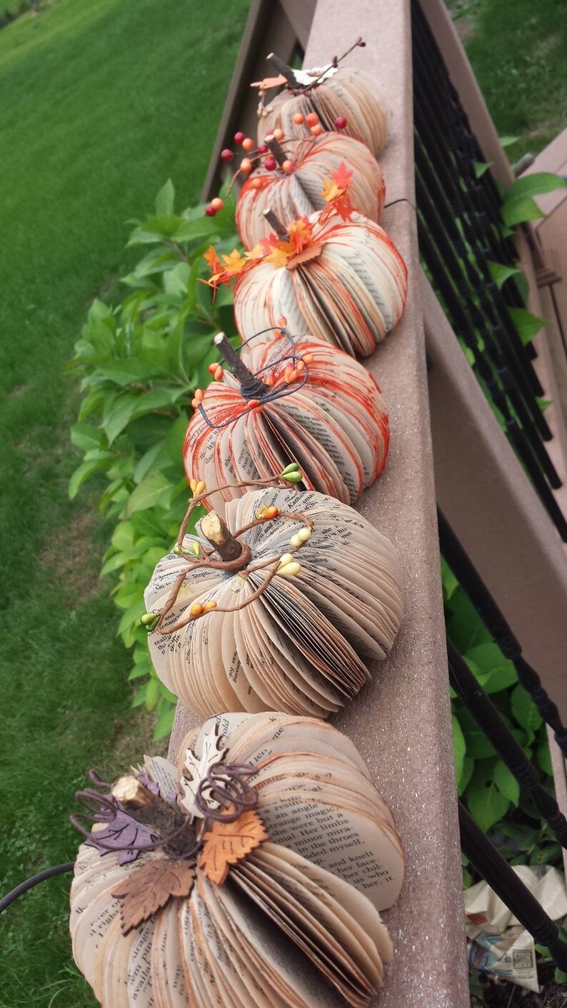 Pumpkins s made from book pages, various embellishments such a pine cones,  berries or twine.  The pumpkins stem is made from a twig branch. Colors available are natural book color and orange,