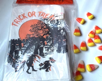 May include: A package of 40 large white paper Trick or Treat bags featuring a black and orange graphic of a graveyard, a large moon, and costumed figures. The packaging includes the text Trick or Treat. Twelve pieces of yellow, orange, and white candy corn are scattered to the right of the bag.