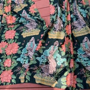 May include: Black fabric with a repeating pattern of pink flowers, green leaves, and stylized birds in pots. The fabric has a textured, almost quilted look.