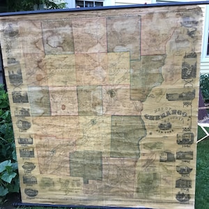 May include: An antique map of Seneca County, New York, printed in 1855. The map is divided into sections, each showing a different part of the county. The map is framed and hanging on a wall.