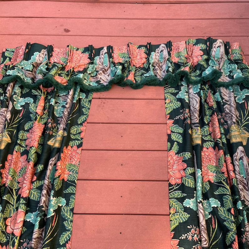 May include: A pair of green and pink floral curtains with a ruffled top edge. The curtains are made of a soft, flowing fabric and feature a repeating pattern of flowers and leaves.