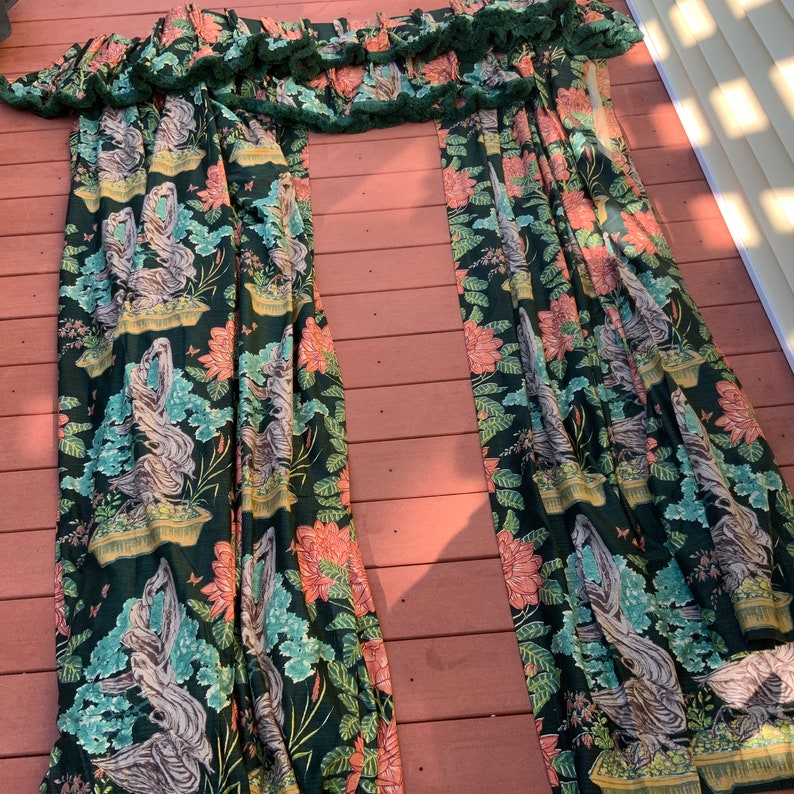 May include: Two green and pink patterned curtains with a ruffled top. The curtains feature a floral design with a repeating pattern of birds and plants.