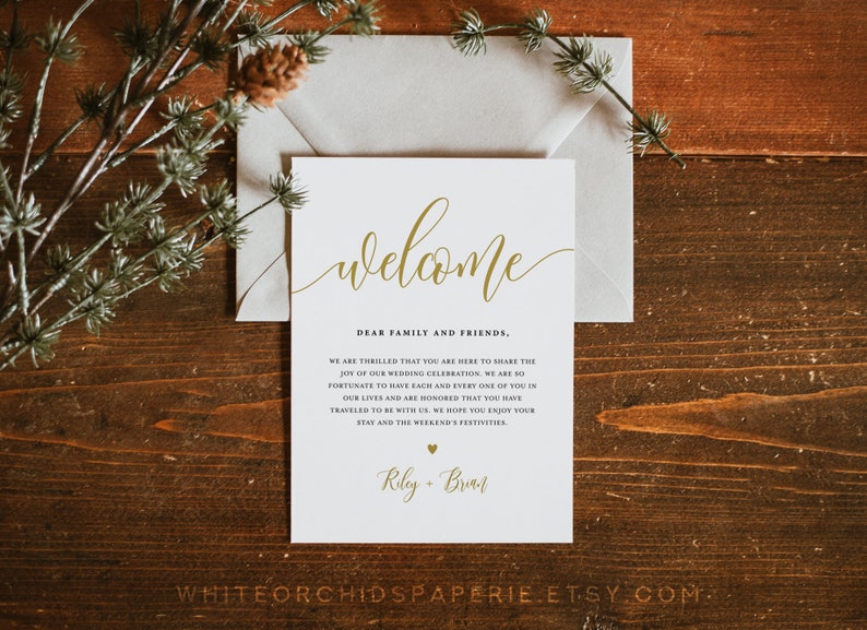 May include: A white welcome sign with gold calligraphy that reads "welcome". The sign also includes the text "Dear family and friends, We are thrilled that you are here to share the joy of our wedding celebration. We are so fortunate to have each and every one of you in our lives and are honoured that you have travelled to be with us. We hope you enjoy your stay and the weekend's festivities. Riley + Brian".