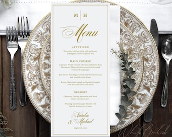 Op de afbeelding: Een witte rechthoekige trouwmenukaart met gouden tekst en een gouden rand. De tekst bevat de initialen M H, het woord Menu en secties voor Appetizer, Main Course en Dessert. Onderaan staan de namen Natalia & Michael vermeld.