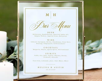 Op de afbeelding: Een rechthoekig glazen bord in een goudkleurig metalen frame met een witte barmenu-kaart met gouden tekst. Het menu bevat de initialen M H, de kop Bar Menu, en lijsten voor bier, wijn, cocktails en sterke drank, eindigend met Melissa & Austin 08.18.20XX.
