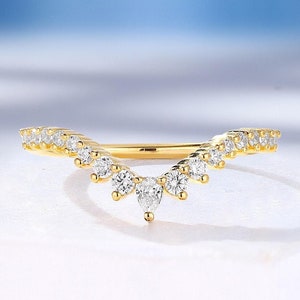 May include: A delicate gold band ring with a curved design featuring a row of small round diamonds and a cluster of larger diamonds at the center.