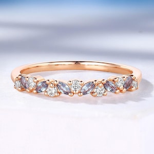 May include: A delicate rose gold band ring with a row of alternating marquise-shaped blue and white gemstones.