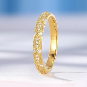 May include: A gold band ring with a delicate design of small diamonds set in a textured pattern.