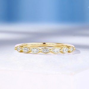 May include: A delicate gold band ring with a row of small, oval-shaped diamonds set in a pave setting.