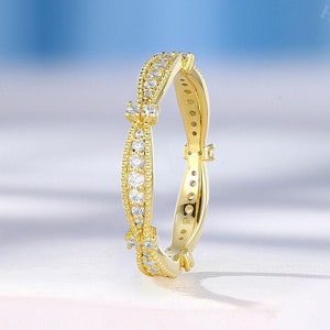 May include: A gold band ring with a delicate, twisted design. The ring is set with small, clear gemstones.