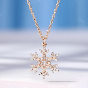 May include: A delicate gold necklace with a snowflake pendant adorned with sparkling clear cubic zirconia stones.