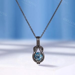 May include: A black chain necklace with a pendant featuring a blue gemstone set in a knot design.