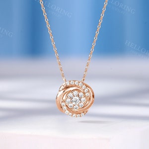 May include: A rose gold necklace with a round pendant featuring a cluster of small diamonds in a swirl design.