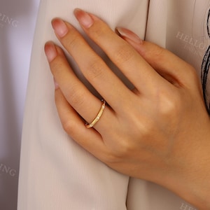 May include: A gold band ring with small clear stones set into the band. The ring is on a person's finger.