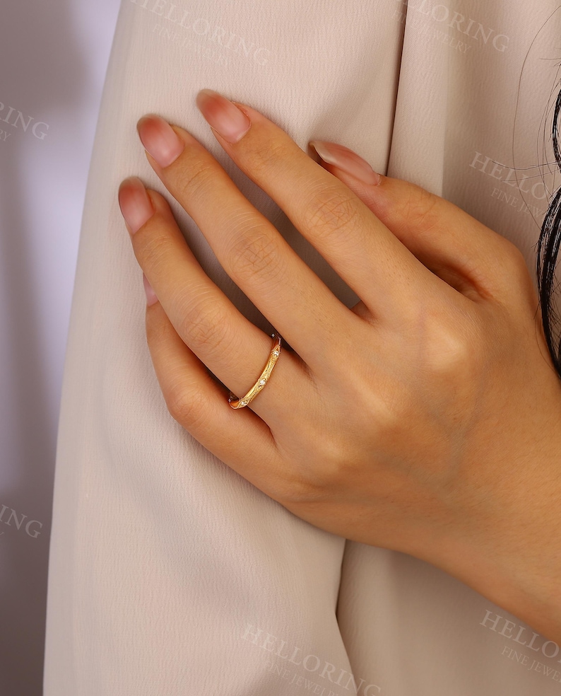 May include: A gold band ring with small clear stones set into the band. The ring is on a person's finger.