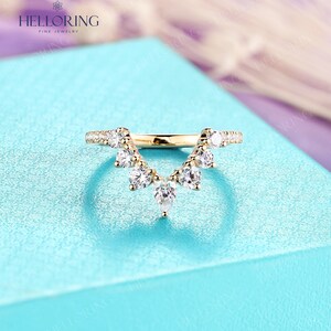 May include: A gold ring with a V-shaped band of small diamonds and a row of larger pear-shaped diamonds hanging from the center.