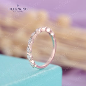 May include: A delicate rose gold band with a row of marquise-shaped diamonds set in a pave setting.