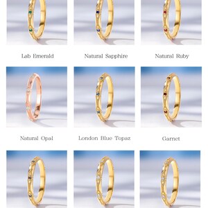 May include: A collection of nine thin metal rings featuring intricate engraved patterns and small, round-cut gemstones. The set includes lab emerald, natural sapphire, natural ruby, natural opal, London blue topaz, garnet, lab alexandrite, aquamarine, and natural diamond options.
