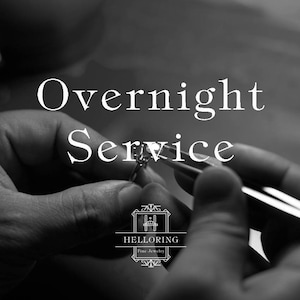 Puede incluir: Imagen en blanco y negro de un joyero trabajando en una pieza de joyería. El texto "Servicio nocturno" se muestra sobre las manos del joyero. El logotipo de Helloring Fine Jewelry se muestra debajo de las manos del joyero.
