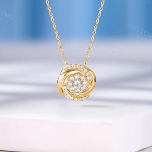 May include: A gold chain necklace with a round pendant featuring a swirl design and a cluster of small diamonds.