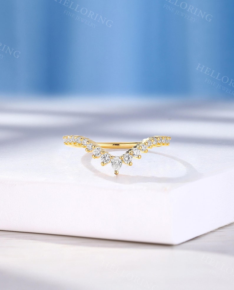 May include: A delicate gold band ring with a curved design featuring a row of small round diamonds and a cluster of larger diamonds at the center.