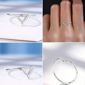 May include: A silver-toned ring with a V-shaped design. The ring features a series of small, clear gemstones set along the V, creating a sparkling effect. The band is thin and polished, and the ring is shown from multiple angles.