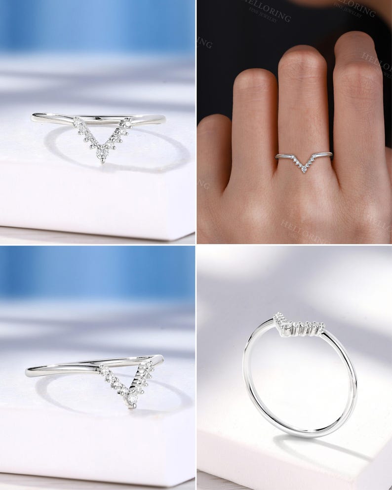 May include: A silver-toned ring with a V-shaped design. The ring features a series of small, clear gemstones set along the V, creating a sparkling effect. The band is thin and polished, and the ring is shown from multiple angles.
