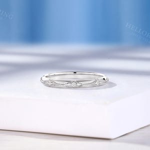 May include: A silver-toned band ring featuring a series of repeating marquise-shaped motifs along the outer surface. Each motif is accented with small, clear, round-cut stones and bordered by delicate milgrain detailing along the edges.