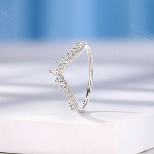 May include: A silver ring with a V-shaped band of small, clear stones. The ring is on a white surface.