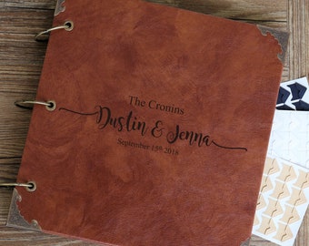 May include: A brown leather photo album with gold rings and a personalized inscription that reads "The Cronins Dustin & Jenna September 15th 2018".
