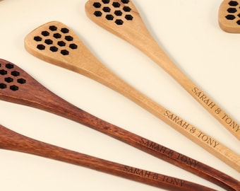 Puede incluir: Cucharones de miel de madera en varios tonos marrones, con diseño de panal en el extremo de la cuchara. El texto "SARAH & TONY" está grabado en el mango. Dispuestos sobre una superficie clara.