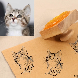 Può includere: Un timbro in legno con un disegno di gatto e il nome "Luna" stampato su una superficie marrone. Il timbro viene utilizzato per creare più impressioni dell'immagine del gatto. Un primo piano di un gattino è nell'angolo in alto a sinistra.