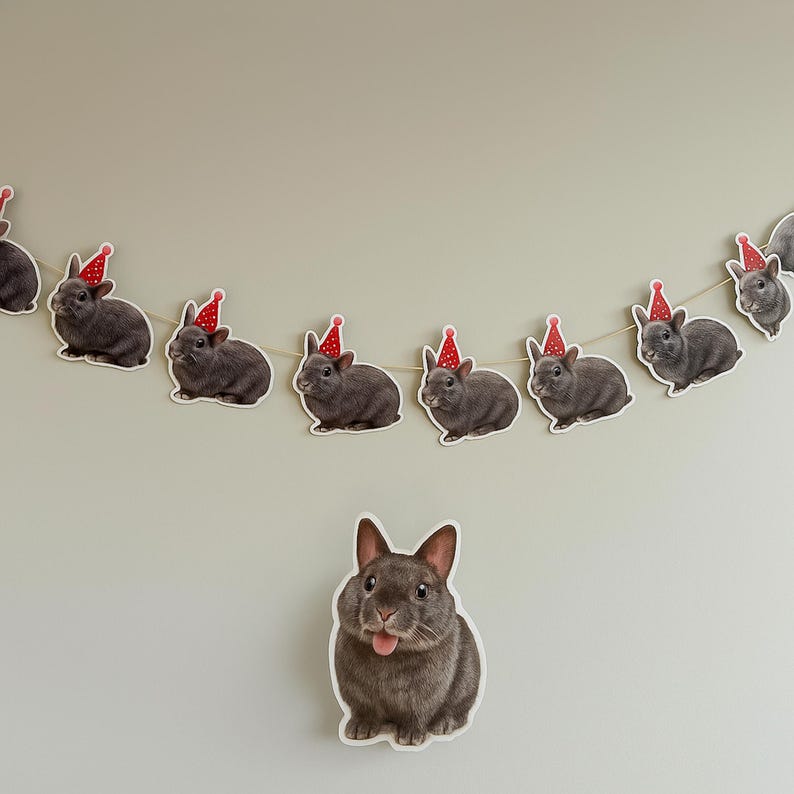 May include: A garland of gray rabbits wearing red party hats. The rabbits are all facing the same direction and are evenly spaced apart. There is a single gray rabbit in the center of the image, not wearing a hat, with its tongue sticking out.