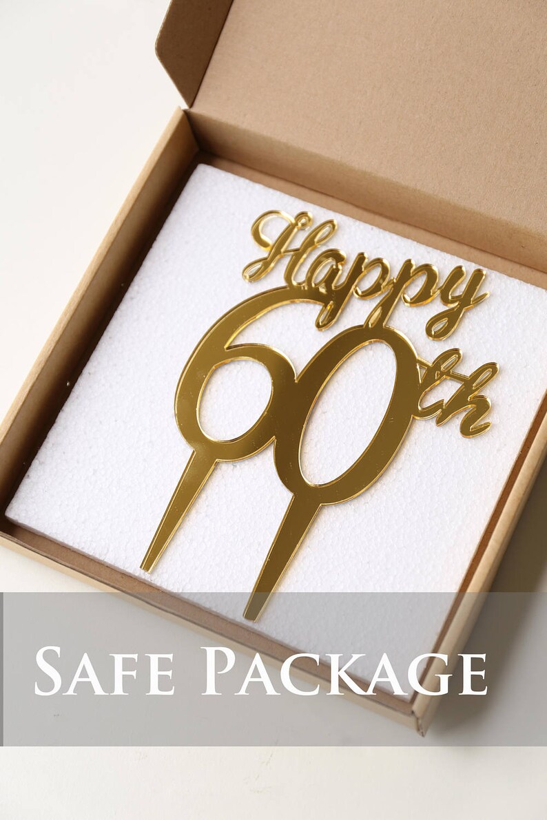 May include: Gold mirror acrylic cake topper with the words "Happy 60th" in a cursive font. The topper is packaged in a white foam box.