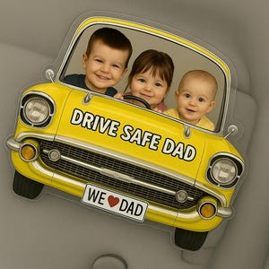 Op de afbeelding: Een gele auto-vormige decoratie met drie lachende kinderen erin. De auto heeft de tekst "DRIVE SAFE DAD" en "WE ❤️ DAD". De afbeelding staat tegen een grijze achtergrond.