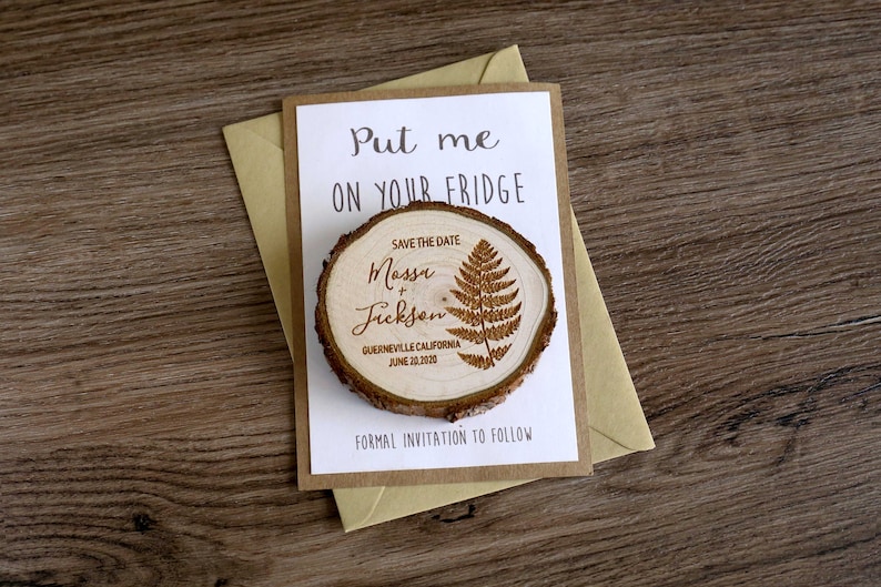 Puede incluir: Un im&aacute;n de madera para guardar la fecha con un dise&ntilde;o de helecho. El im&aacute;n dice "Save the Date" e incluye los nombres "Masse & Jickson", la ubicaci&oacute;n "Guerneville, California" y la fecha "June 20, 2020". El im&aacute;n va acompa&ntilde;ado de una tarjeta que dice "Put me on your fridge" y "Formal invitation to follow".