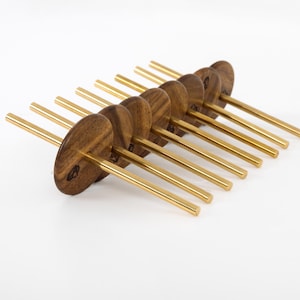 Op de afbeelding: Een set van acht cocktailprikkers van hout en messing. Elke prikker heeft een ronde, donkere houten bovenkant en een messing steel. De prikkers zijn in een rij gerangschikt tegen een witte achtergrond, wat hun elegante ontwerp benadrukt.