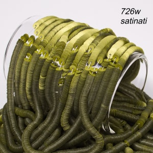 May include: Olive green satin sequins spilling from a clear glass container. The sequins are round and have a shiny finish. The text "726w satinati" is visible in the upper right corner. These sequins are ideal for craft projects.