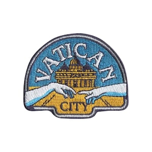 May include: An embroidered patch featuring a blue sky background with the text VATICAN CITY in white letters. The design includes a golden depiction of St. Peter's Basilica and two white hands reaching toward each other over a golden ground.