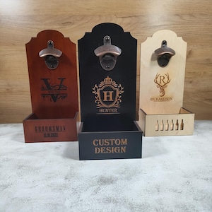 May include: Three wooden bottle openers with attached catch boxes. The openers are in shades of brown, black, and natural wood. Each has a metal opener and personalized engraving, including names and initials. The catch boxes are designed to collect bottle caps.