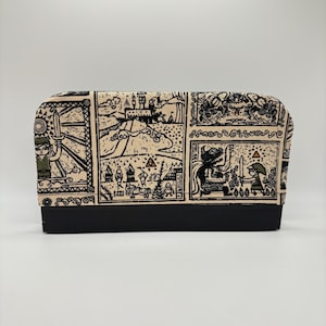 May include: A rectangular, beige and black cosmetic bag featuring a map-like design with various illustrations. The bag has a black base and a zipper closure. The illustrations include figures with swords, castles, and other fantasy elements.