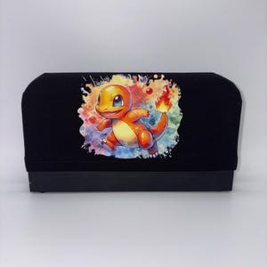 May include: Black screen printing squeegee with a colorful watercolor image of Charmander, a popular character from the Pokémon franchise. The image features an orange Charmander with a flame on its tail, set against a vibrant background of blues, reds, and yellows.