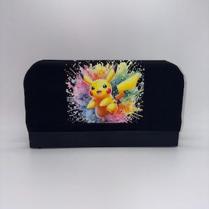 May include: Black screen printing squeegee with a colorful Pikachu graphic. The design features a yellow Pikachu character with a splash of vibrant colors including pink, blue, and yellow. The squeegee is used for screen printing.
