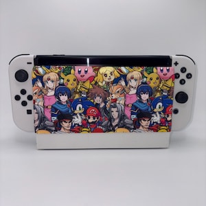 May include: A white video game console dock featuring a fabric cover with a colorful, repeating pattern of various animated characters including Mario, Sonic, Pikachu, Kirby, and other figures from popular video game franchises on a blue background.